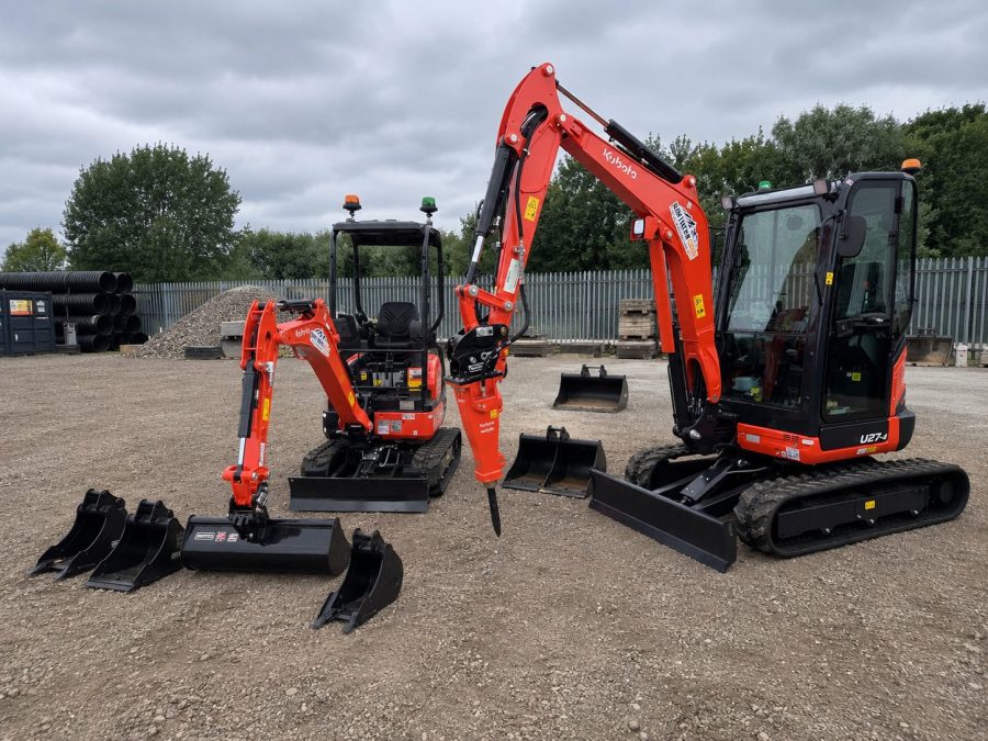 Kubota U17-5 and U27-4 mini excavators standing together with three buckets and a hydraulic breaker laid out in front of them